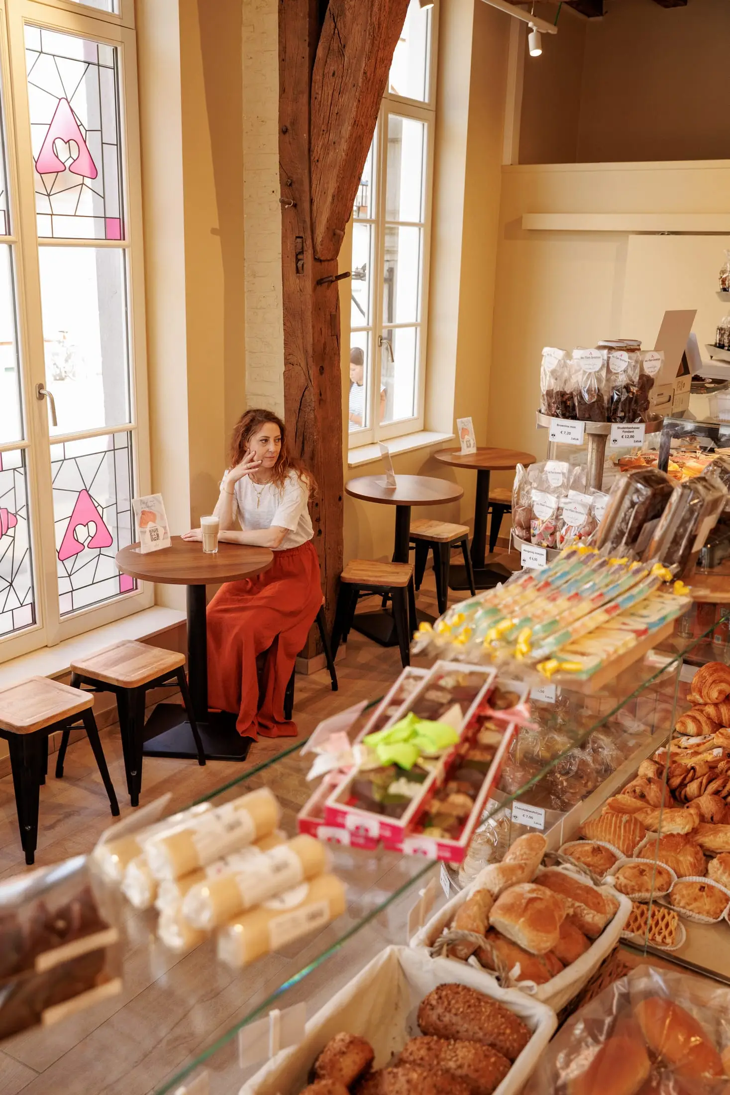 Klant drinkt een latte aan het raam van een bakkerij