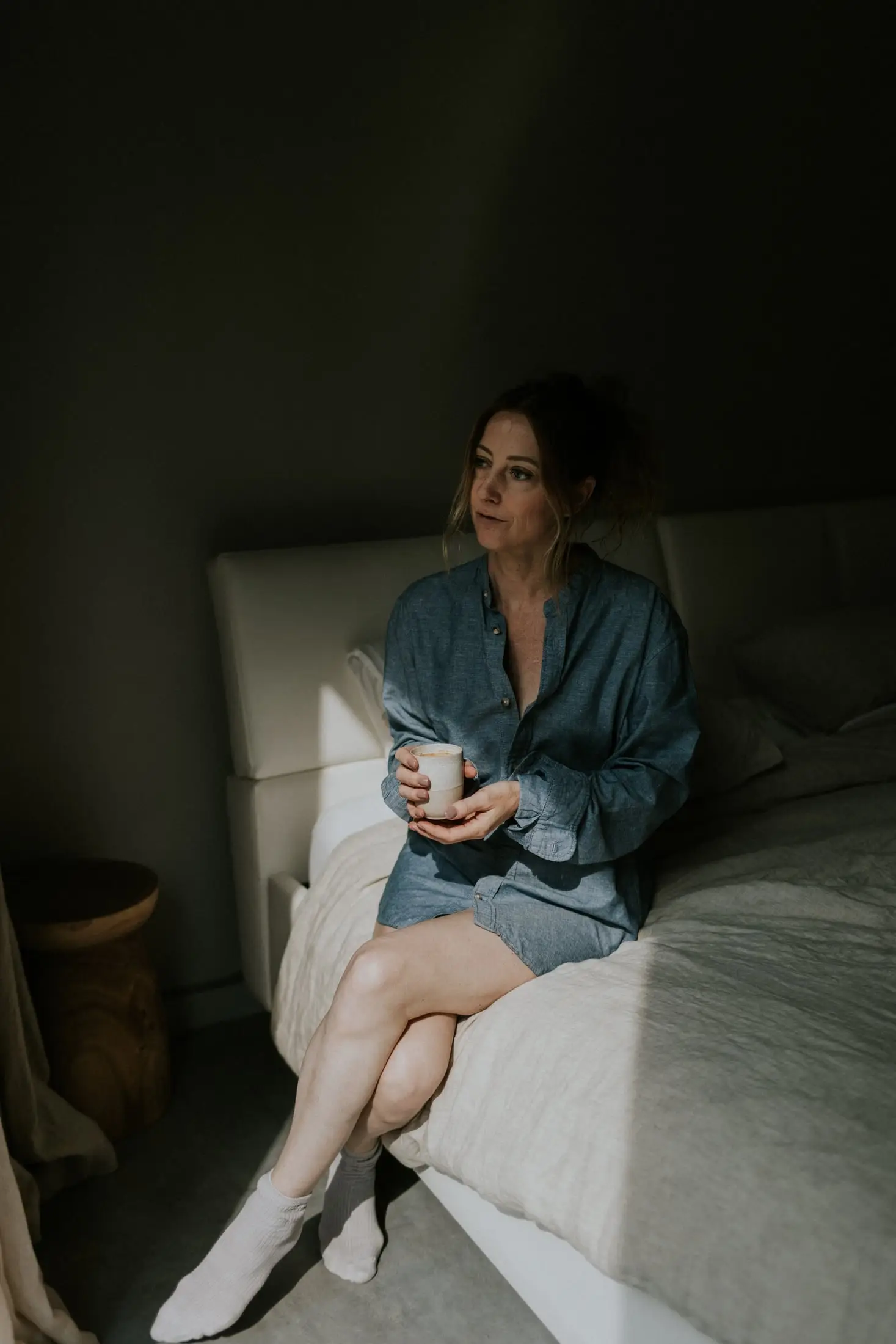 Gaste drinkt een koffie op de rand van het hotelbed