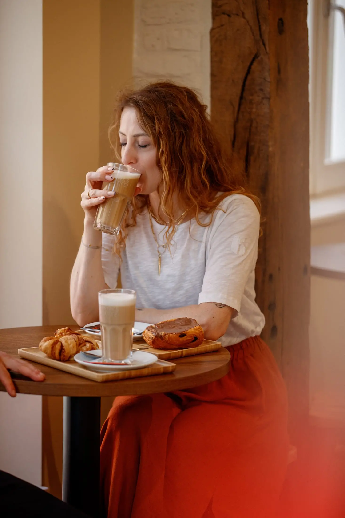 Gast geniet van een latte macchiato aan een tafeltje