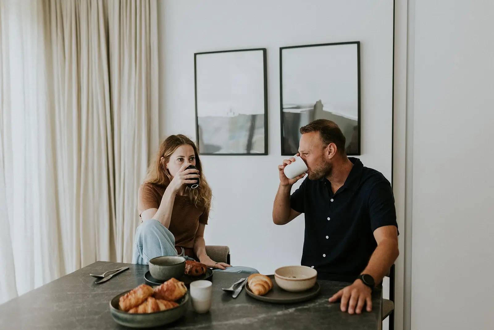 Koppel drinkt koffie aan de ontbijttafel met croissants